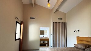 Une chambre à coucher avec un lit, une table de chevet, un miroir et une fenêtre.