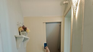Ein Badezimmer mit einem weißen Waschbecken, einem Spiegel und einem Regal mit Blumen.