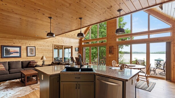 Un intérieur de cabine spacieux comprenant une cuisine, un coin repas et de grandes fenêtres donnant sur un lac.