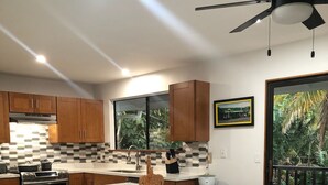 A modern kitchen with a large island, wooden cabinets, and a view of the outdoors. - Steps from the beach, 2-bedroom house with WiFi, AC in awesome Puako Beach (Waimea)