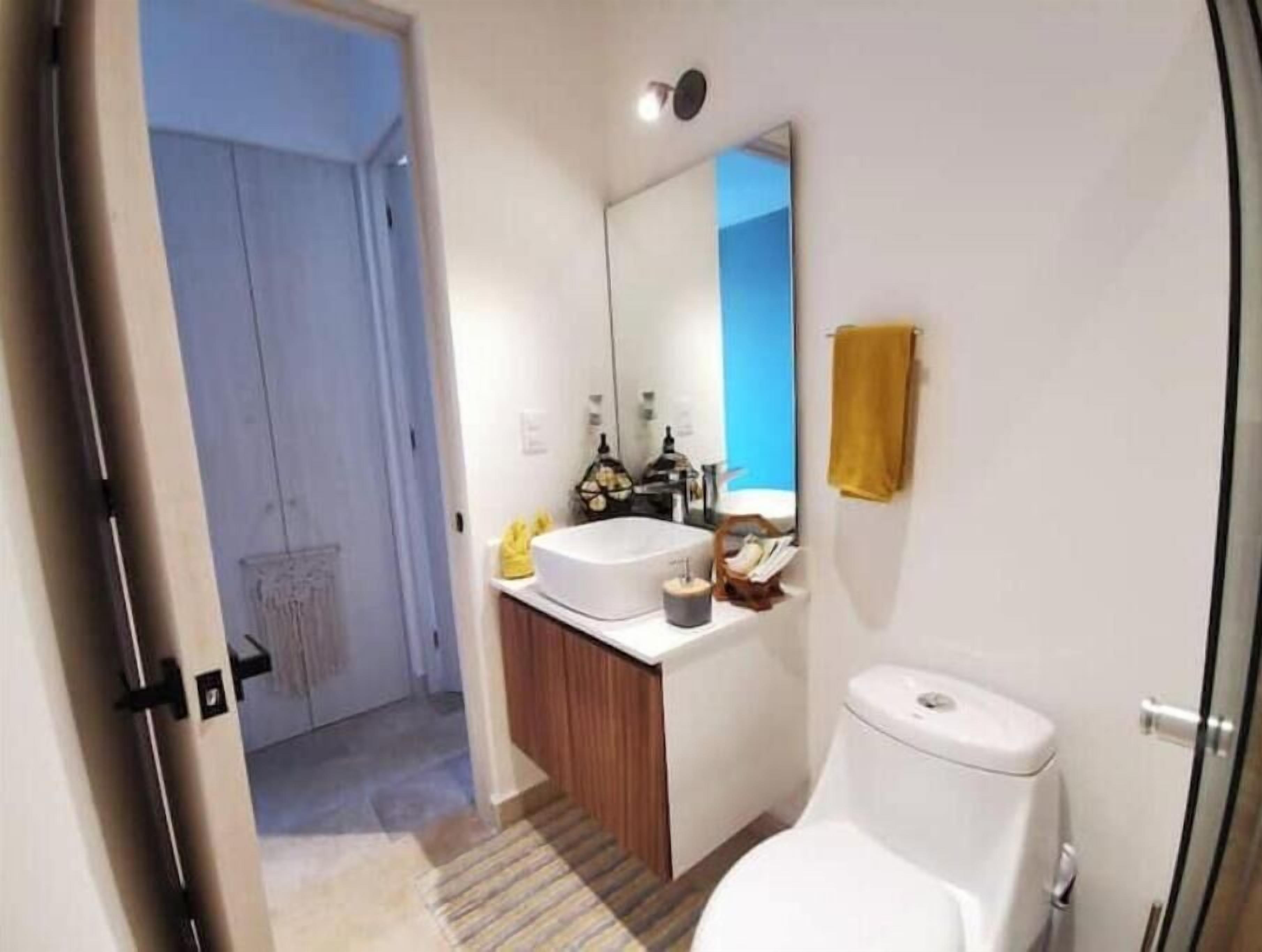 A modern bathroom with a white toilet, a sink, and a mirror.