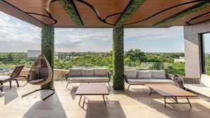 A rooftop terrace with a hanging chair, sofas, and a table. - Tulum City Apartments M-123 (Tulum)