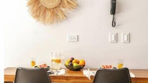 A dining area with a wooden table, two black chairs, and two wall-mounted decorative sunburst mirrors. - Tulum City Apartments M-123 (Tulum)