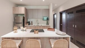 A modern kitchen with a central island, built-in cabinets, and a dark wooden door.