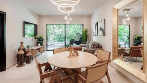 A modern dining area with a round table, wooden chairs, and a unique chandelier.