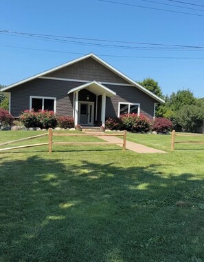 A two-story building with a front porch, a door, and windows.