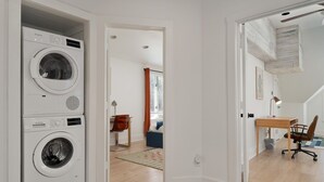 Lavandería con dos lavadoras Bosch, un escritorio de madera y una silla en un apartamento moderno.