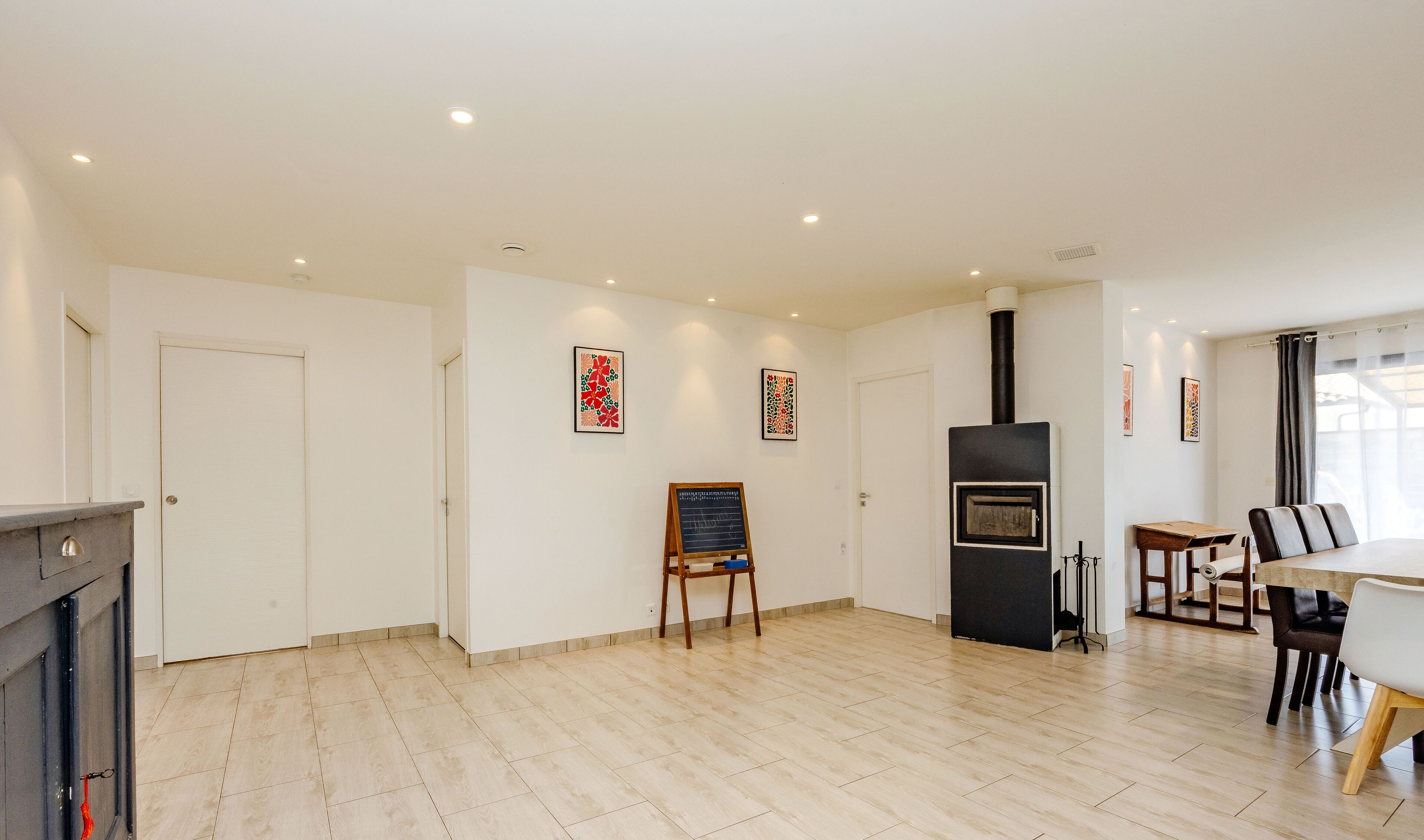 A spacious room with a fireplace, a dining area with a table and chairs, and a black wood-burning stove.