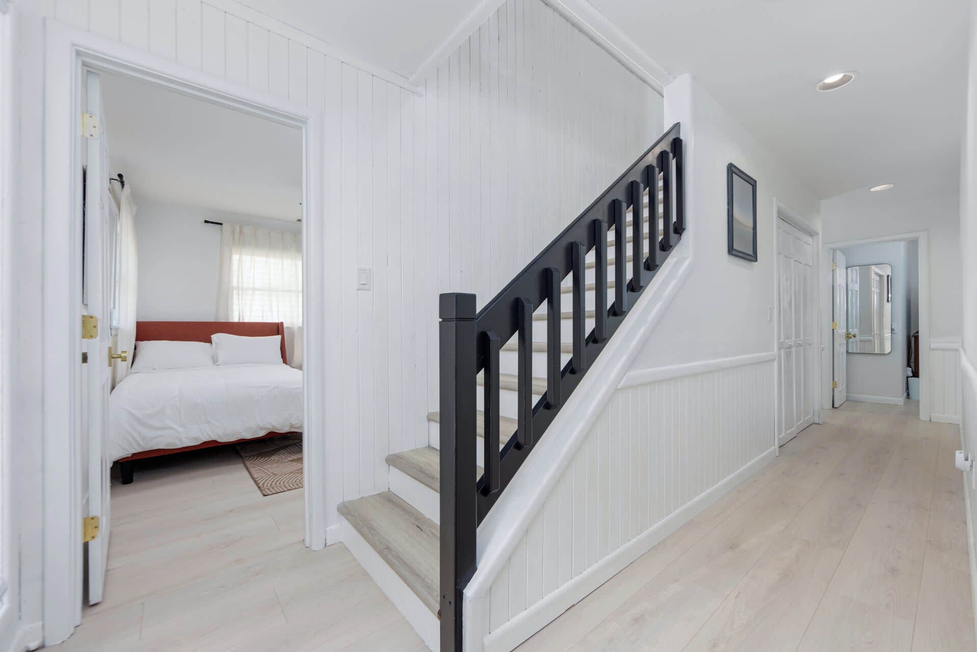 A hotel room with a bed, a staircase, and a hallway.