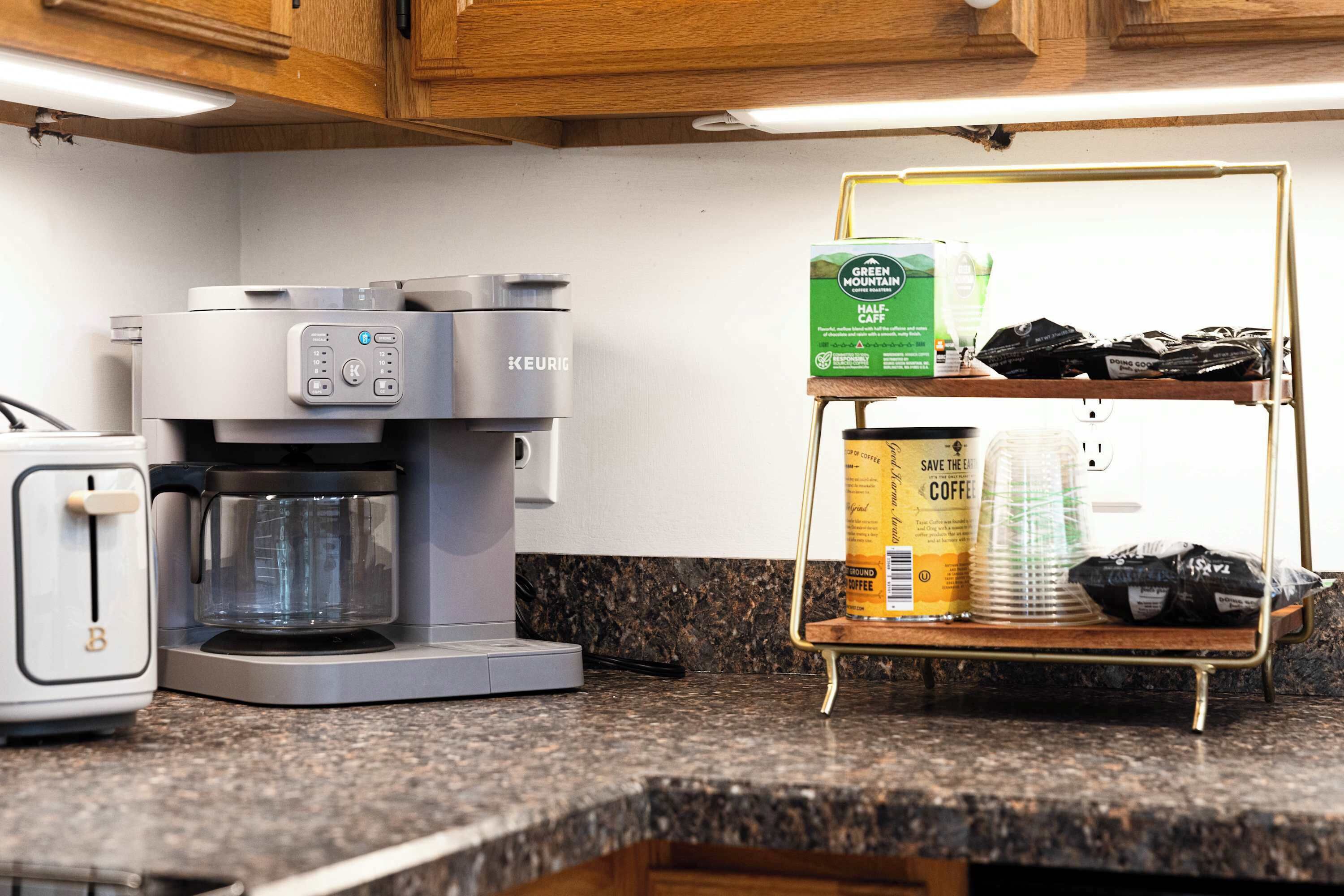 A kitchen with a coffee maker, a toaster, and a shelf with coffee pods and a box of green mountain half & half.