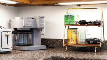 A kitchen with a coffee maker, a toaster, and a shelf with coffee pods and a box of green mountain half & half.