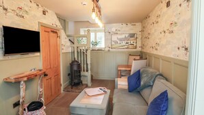 Ein gemütliches Wohnzimmer mit Fernseher, Kamin und einer Couch mit Kissen.