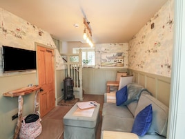 Ein gemütliches Wohnzimmer mit Fernseher, Kamin und einer Couch mit Kissen.
