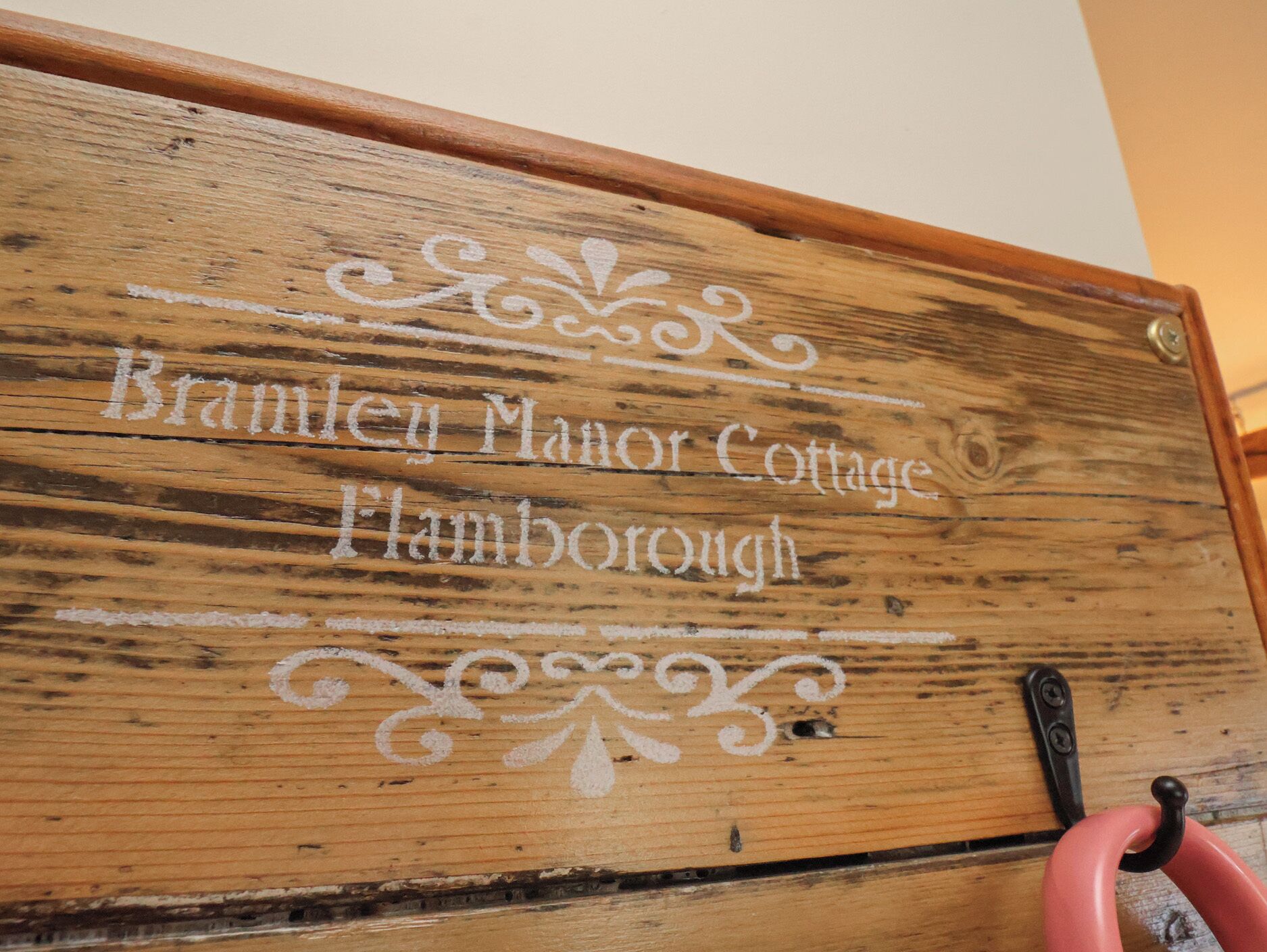 Une plaque en bois portant l’inscription gravée « Brambley Manor Cottage Flamborough ».
