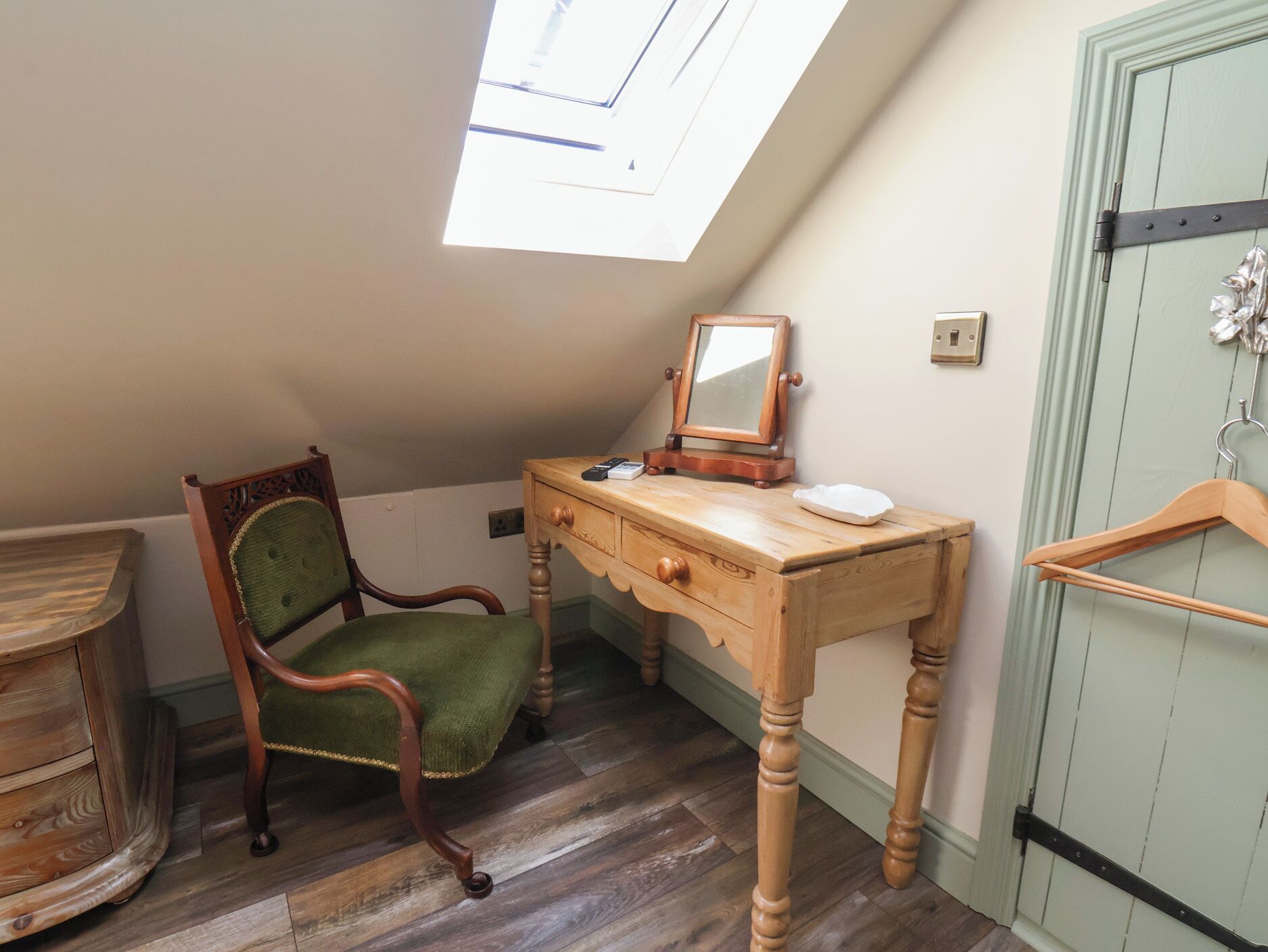 A room with a wooden desk, a chair, a mirror, and a door.