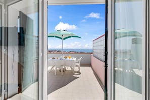 A balcony with a table and chairs, a green umbrella, and a clear view of the sea. - Seaview & Pool Retreat Il Poggio (Andora)
