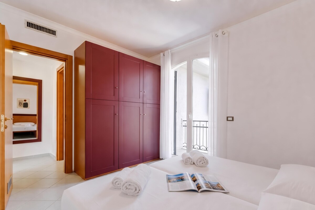 A hotel room with a bed, a wardrobe, a bathroom, and a balcony.