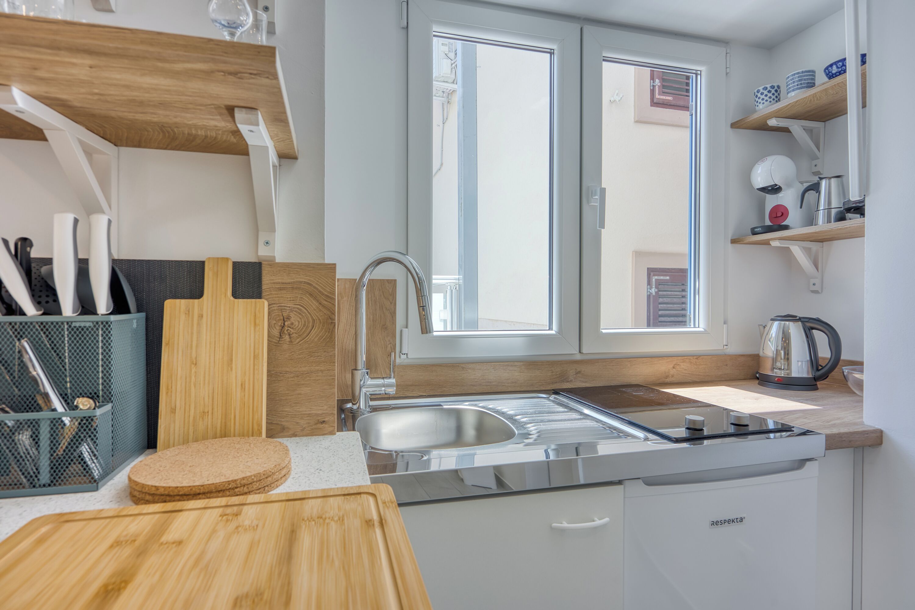 A modern kitchen with a stainless steel sink, wooden countertop, and a built-in dishwasher.
