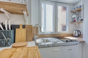Une cuisine moderne dotée d’un évier en acier inoxydable, d’un plan de travail en bois et d’un lave-vaisselle encastré.