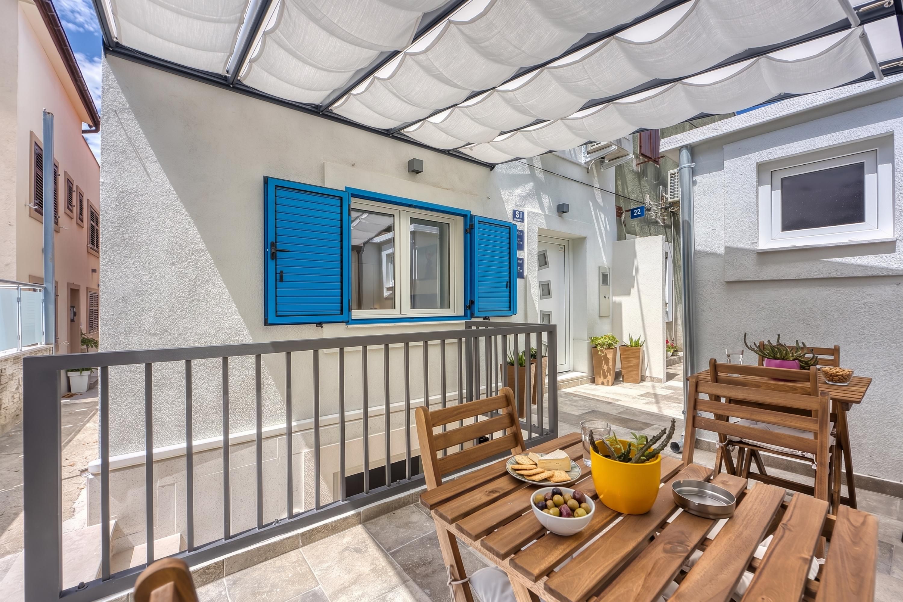 A balcony with a wooden table, chairs, and a bowl of olives.