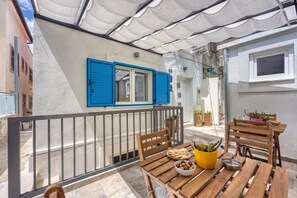 A balcony with a wooden table, chairs, and a bowl of olives. - Mali Lošinj Summer Breeze (Mali Losinj)
