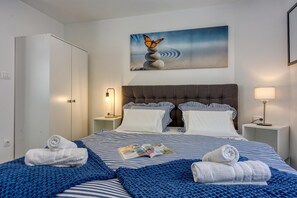 A hotel room with a bed, two bedside tables, a nightstand, a wardrobe, and a painting on the wall. - Mali Lošinj Summer Breeze (Mali Losinj)
