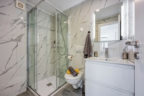 Une salle de bain moderne avec une douche à parois de verre, des toilettes et un meuble-lavabo avec un miroir.