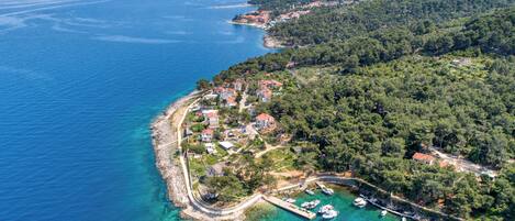 An aerial view of a coastal village with houses, a pier, and boats.