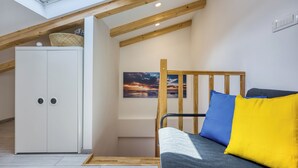 Quarto em estilo loft com claraboia, cama beliche, guarda-roupa e uma pintura.