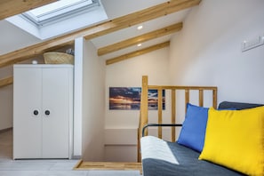 Un dormitorio tipo loft con tragaluz, una cama litera, un armario y un cuadro.
