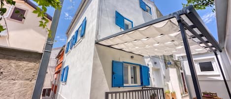 Un edificio residencial con balcón, zona de estar exterior cubierta y vista a la calle.