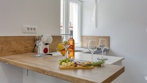 Eine Küchenarbeitsfläche mit Holzbeschichtung, ein Weinglas, eine Flasche Olivenöl und ein Käsebrett mit verschiedenen Zutaten.