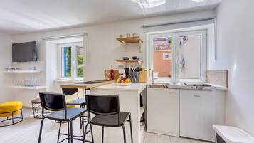 Una cocina moderna con comedor, televisor y vistas al exterior.