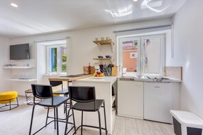 Eine moderne Küche mit Essbereich, einem Fernseher und Blick ins Freie.