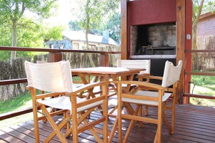 An outdoor deck with wooden furniture and a barbecue grill.