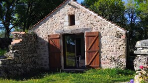 A rustic stone building with a sloped roof and wooden shutters, surrounded by greenery and flowers. - PAULAGITE for 2 to 4 people, view of the Dordogne, near Padirac and Rocamadour (Gintrac)