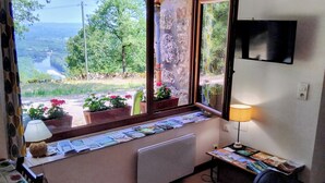 A room with a window view of a river and greenery, a radiator, a table with magazines, and a lamp. - PAULAGITE for 2 to 4 people, view of the Dordogne, near Padirac and Rocamadour (Gintrac)
