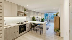 Una cocina moderna con una isla central, electrodomésticos integrados y taburetes de bar.