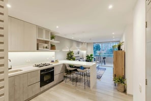 A modern kitchen with a central island, built-in appliances, and bar stools.
