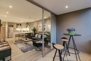 A modern living room with a sofa, coffee table, and a small dining area.
