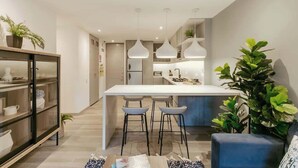 Una cocina moderna con una isla central, luces colgantes y taburetes de bar.