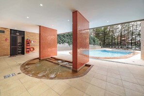 A modern indoor pool area with a hot tub, a separate swimming pool, and a glass-enclosed space with a view of trees. - |EP| Remodeled Apt w/Fast Internet,Balcony,Office (Medellín)