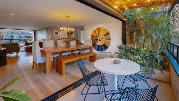 A modern interior with a round dining table, black chairs, a wooden bench, and a large circular wall art piece. - |EP| Premium PH W/Sauna, Jacuzzi, SteamRoom (Medellín)