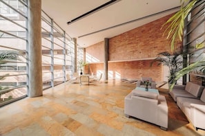 A spacious lobby with a high ceiling, large windows, and a mix of brick and glass walls.