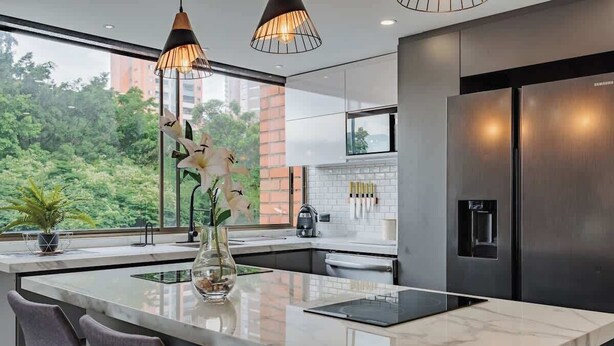 A modern kitchen with a large island, stainless steel appliances, and a view of greenery outside. - |EP| 2BR/W City Views Apt w/Office (Medellín)