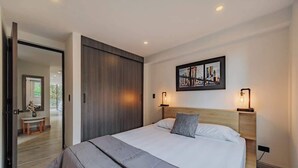 A modern bedroom with a large bed, a wooden wardrobe, a cityscape painting, and bedside lamps. - |EP| 2BR/W City Views Apt w/Office (Medellín)