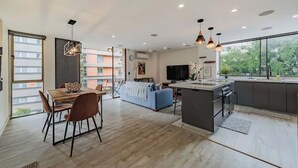 A modern kitchen with a central island, dining area with chairs, and a sofa. - |EP| 2BR/W City Views Apt w/Office (Medellín)