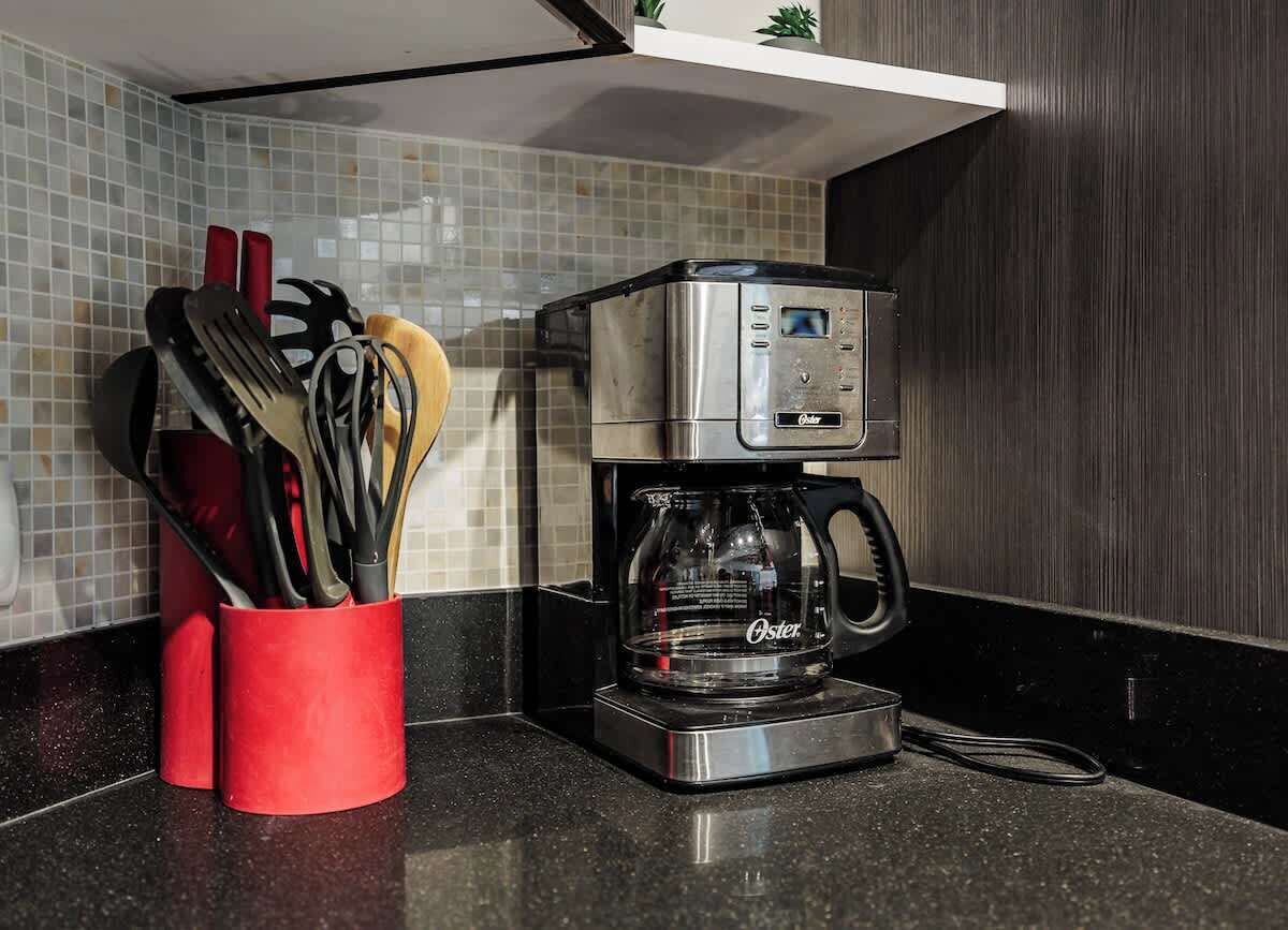 Una moka su un piano di lavoro in cucina, con un portautensili rosso accanto.