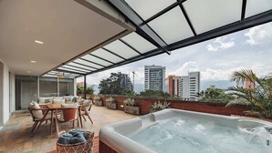 Una terraza en la azotea con un jacuzzi, mobiliario exterior y vistas al horizonte de la ciudad.