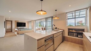 Una cocina moderna con una isla grande, electrodomésticos integrados y una zona de comedor con televisor.
